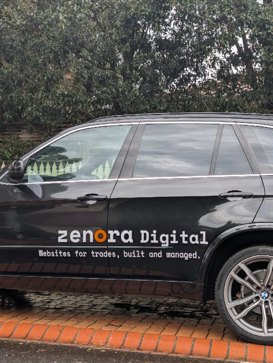 Zenora Digital’s black car, with door signage reading Websites for trades, built and managed.